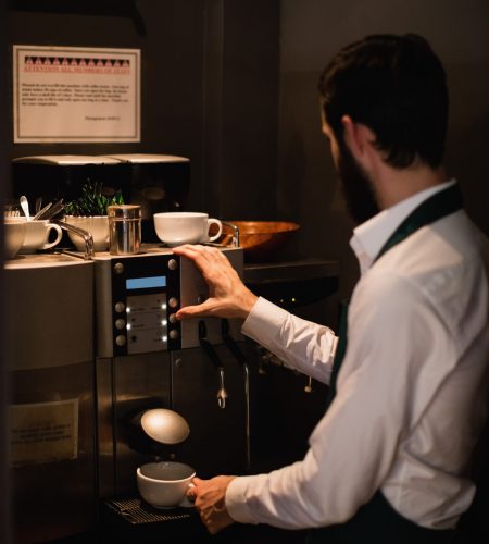 Waiter making cup of coffee from espresso machine in bar